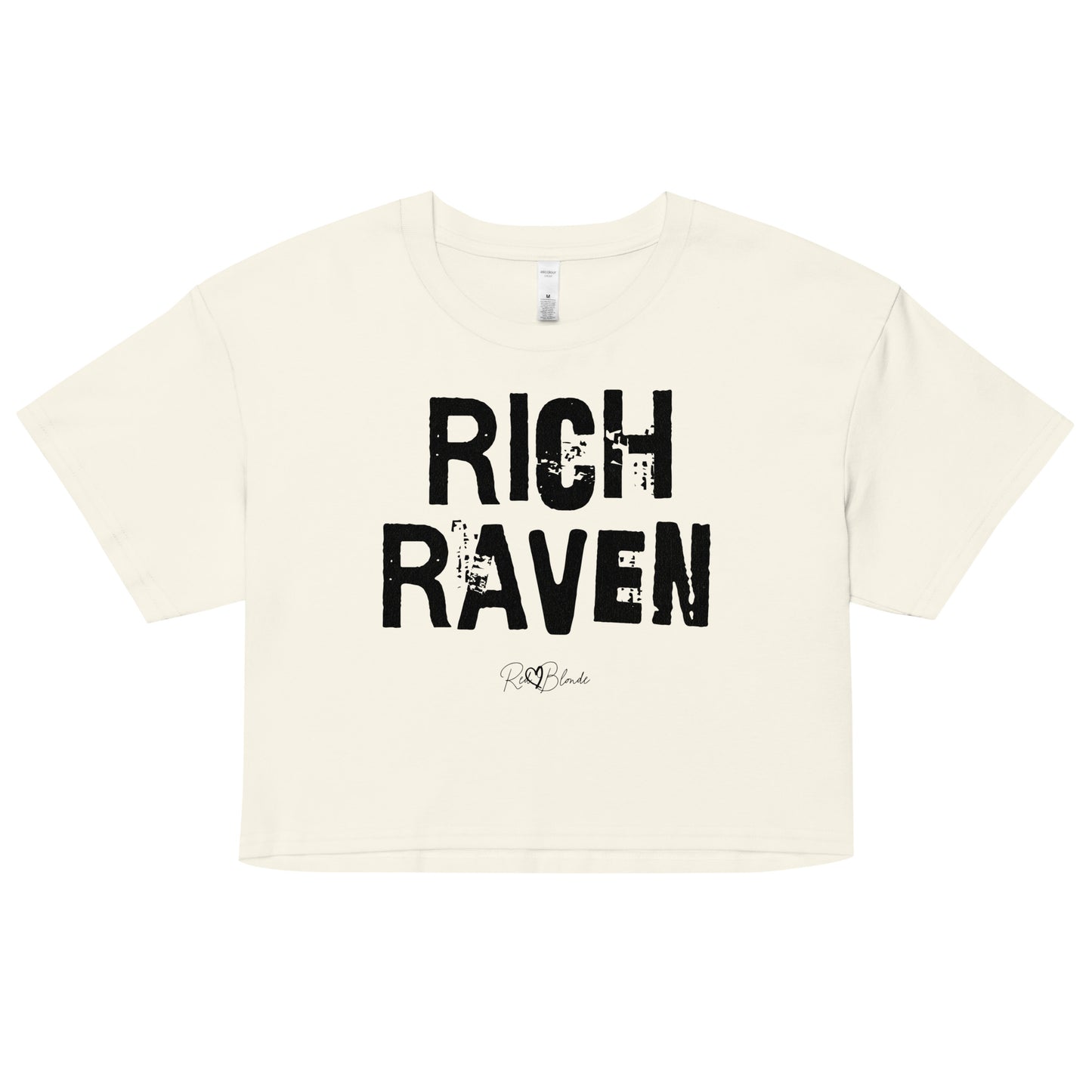 A natural coloured crop top with a relaxed fit, short sleeves, and a wide crew neckline. The front features bold black distressed lettering reading “RICH RAVEN” with the RedBlonde signature logo underneath in black