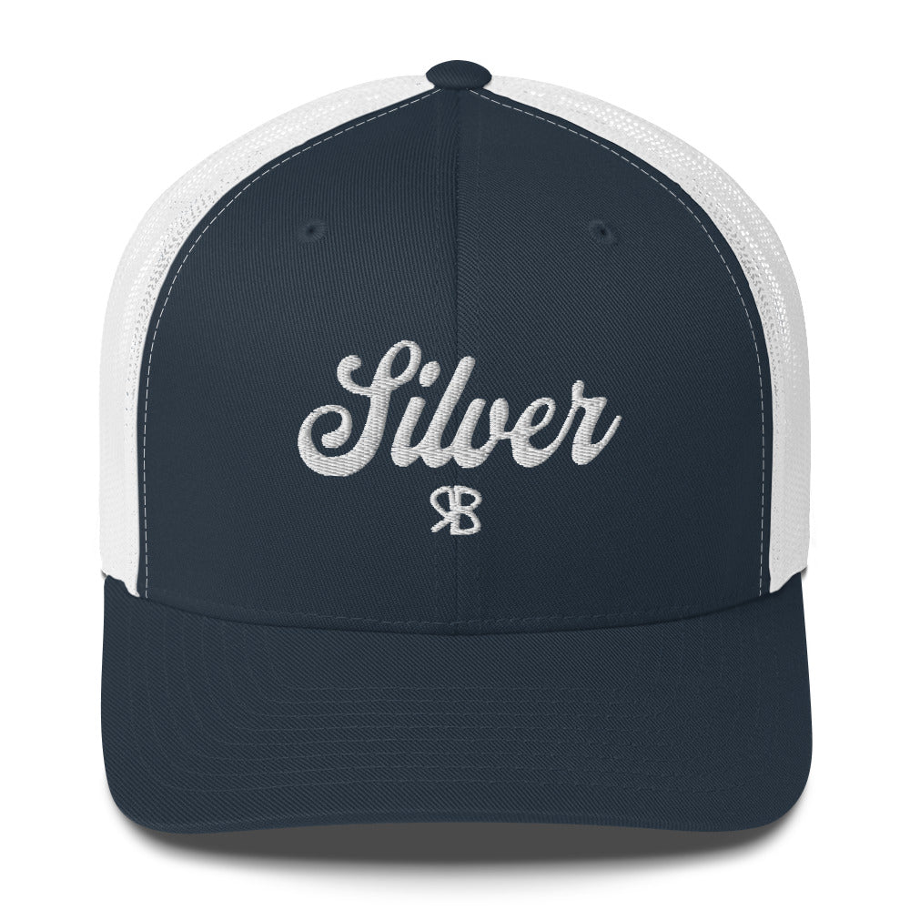 navy/White trucker cap with 'Silver' in white adventurer 01 font on front. Mesh back. Branded RB