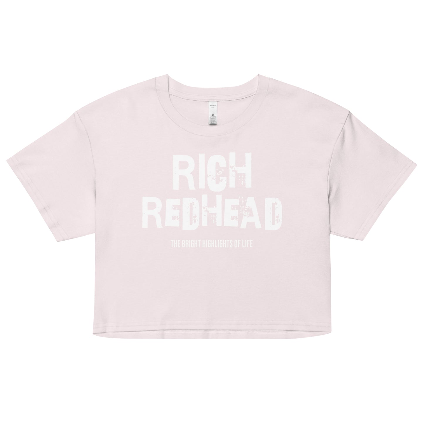An orchid women’s crop top with a relaxed fit, short sleeves, and a wide crew neckline. The front features bold black distressed lettering reading “RICH REDHEAD” with the tagline “THE BRIGHT HIGHLIGHTS OF LIFE” in smaller text below.