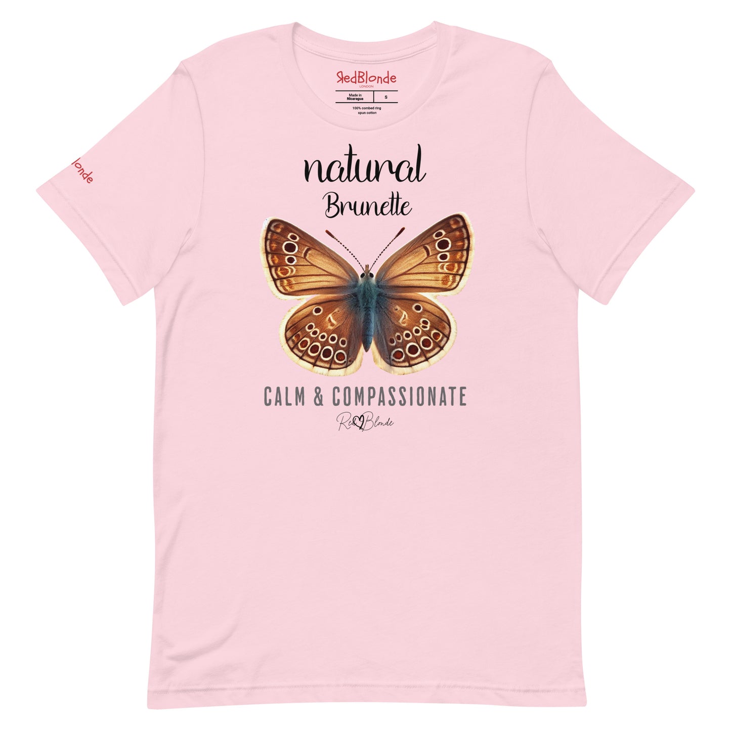 Flatlay of pale pink unisex relaxed fit t-shirt with the words natural brunette in arionna font above a graphic of a brunette brown butterfly with 'CALM & COMPASSIONATE' below in adventurer 06 font signed off by RedBlonde. Branded RedBlonde London on inside neck and right sleeve