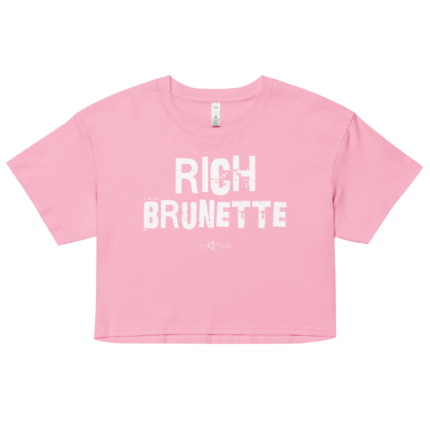 pink crop top with a relaxed fit, short sleeves, and a wide crew neckline. The front features bold white distressed Ed Gein lettering reading “RICH BRUNETTE” with the RedBlonde signature logo underneath in white