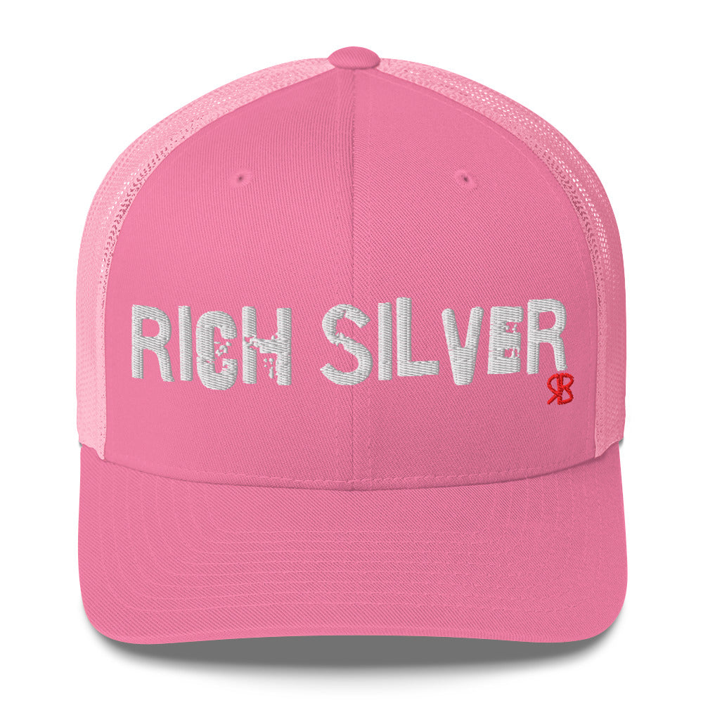 pink mesh-back trucker cap with the bold distressed text “RICH SILVER” embroidered in white across the front, and a small red “RB” logo detail beneath the text. The cap has a structured front panel and curved brim