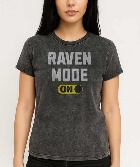 raven head model wears black denim-style unisex t-shirt with bold distressed white Univercity font reading “Raven Mode” and a yellow on/off switch graphic in the “On” position beneath. The design includes subtle worn texture for a vintage look. Branded RedBlonde London in red on inside neck and right sleeve