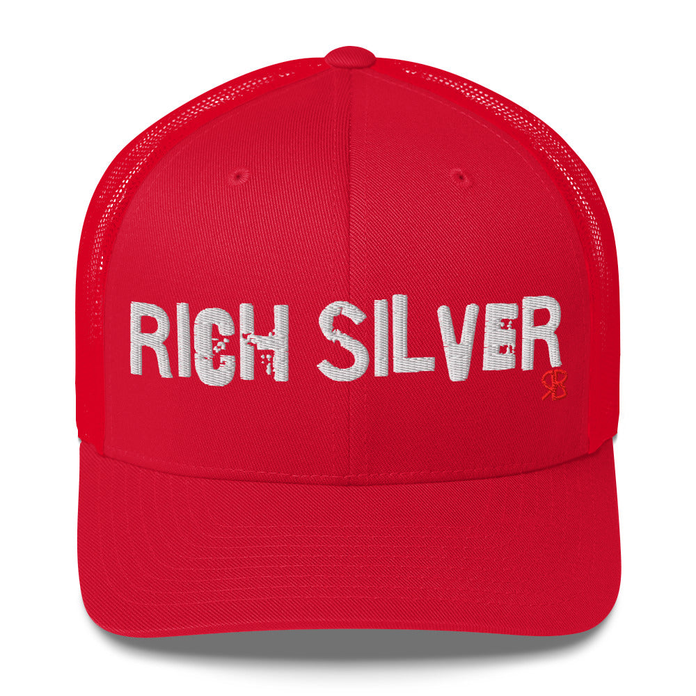 red mesh-back trucker cap with the bold distressed text “RICH SILVER” embroidered in white across the front, and a small red “RB” logo detail beneath the text. The cap has a structured front panel and curved brim