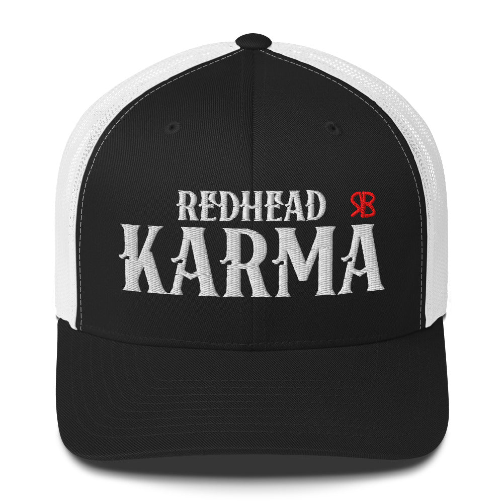 black/white retro trucker cap with mesh back. The front features bold white embroidered text reading "REDHEAD KARMA" with a small red RB logo to the right.