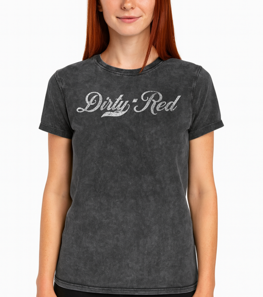 Redhead wears a black unisex loose-fit denim wash t-shirt with vintage Coca-Cola-inspired milkstore script in white reading ‘Dirty Red’ on the front. Branded RedBlonde on the inside neck and right shoulder in red