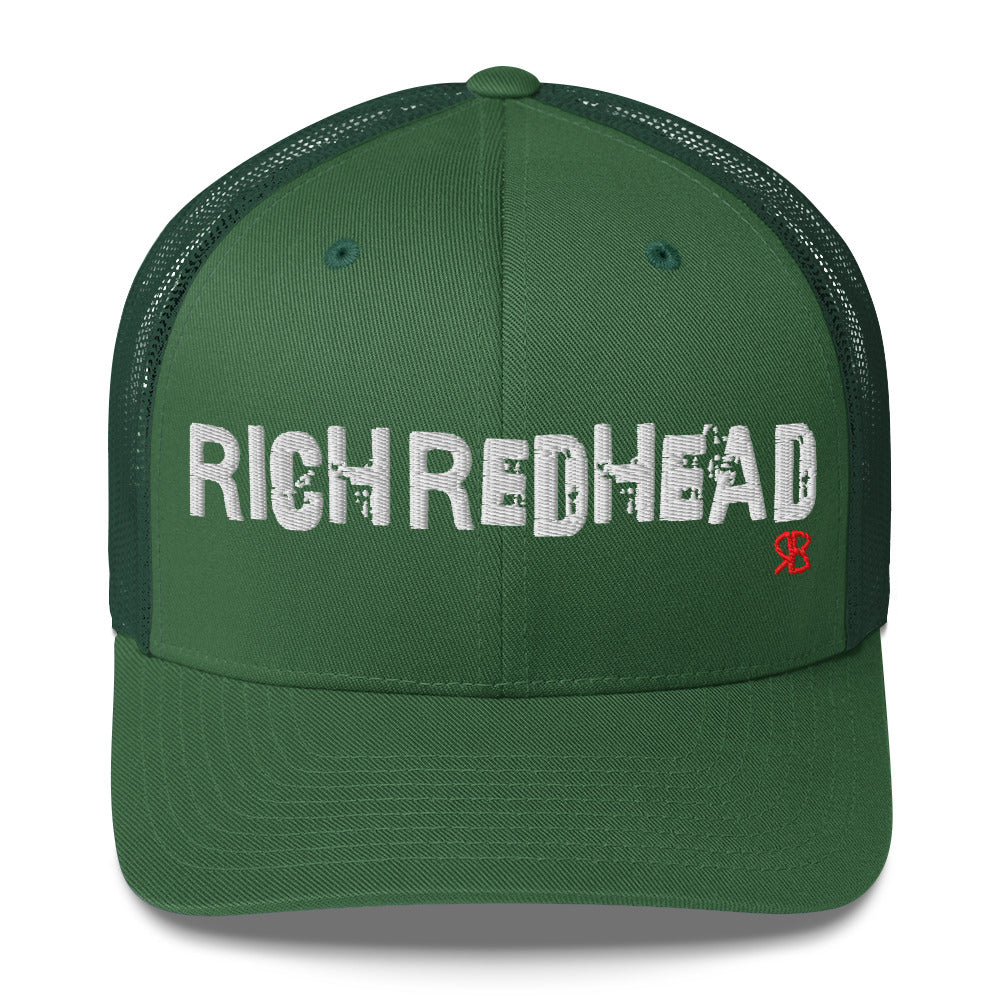 green trucker cap with the bold distressed text “RICH REDHEAD” embroidered in white across the front, and a small red “RB” logo detail beneath the text. The cap has a structured front panel and curved brim