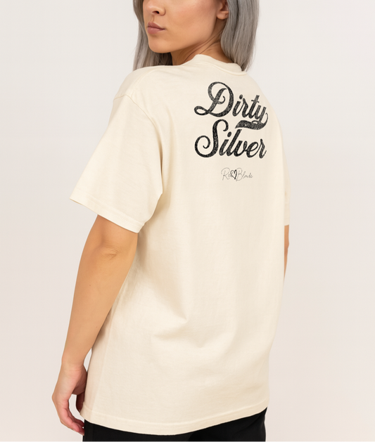 Silver haired woman wears a Boff-white vintage wash oversized unisex T-shirt with bold black Milkstore 01 vintage-style script reading “Dirty Silver” and the RedBlonde signature logo beneath, plus a small RedBlonde logo detail on the right sleeve.