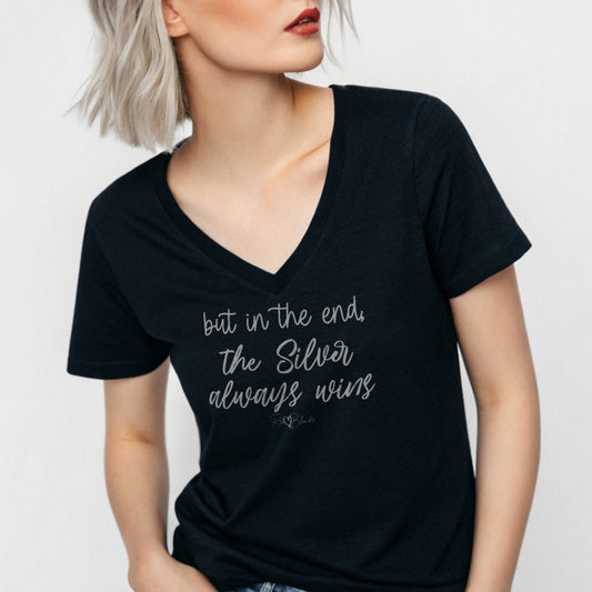 silver haired woman wears a black women's v-neck relaxed fit t-shirt featuring the handwritten-style slogan “but in the end, the Silver always wins” in Hillbear font in grey text across the chest, signed off RedBlonde. Branded “RedBlonde London on inside the collar and on the right sleeve
