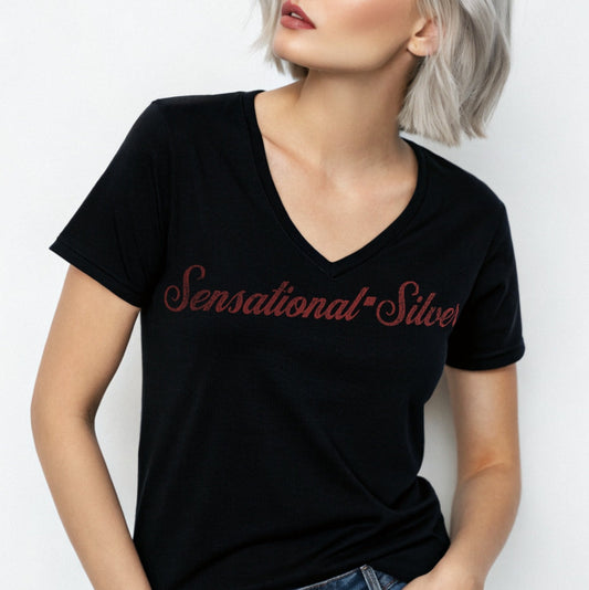silver haired woman wears black women's relaxed fit v-neck slogan t-shirt with 'Sensational Silver' in milkshake script red font. Branded RedBlonde in red on inside neck and right sleeve