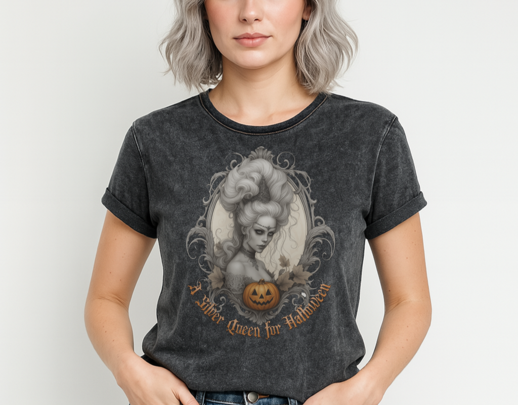 Black acid-wash unisex T-shirt featuring a gothic-style illustration of a silver-haired woman with an elaborate beehive hairstyle, framed by ornate scrollwork, autumn leaves, and a carved pumpkin. The design is captioned with the text ‘A Silver Queen for Halloween’ in vintage Dark Angle lettering. Branded RedBlonde in red on inside neck and right sleeve