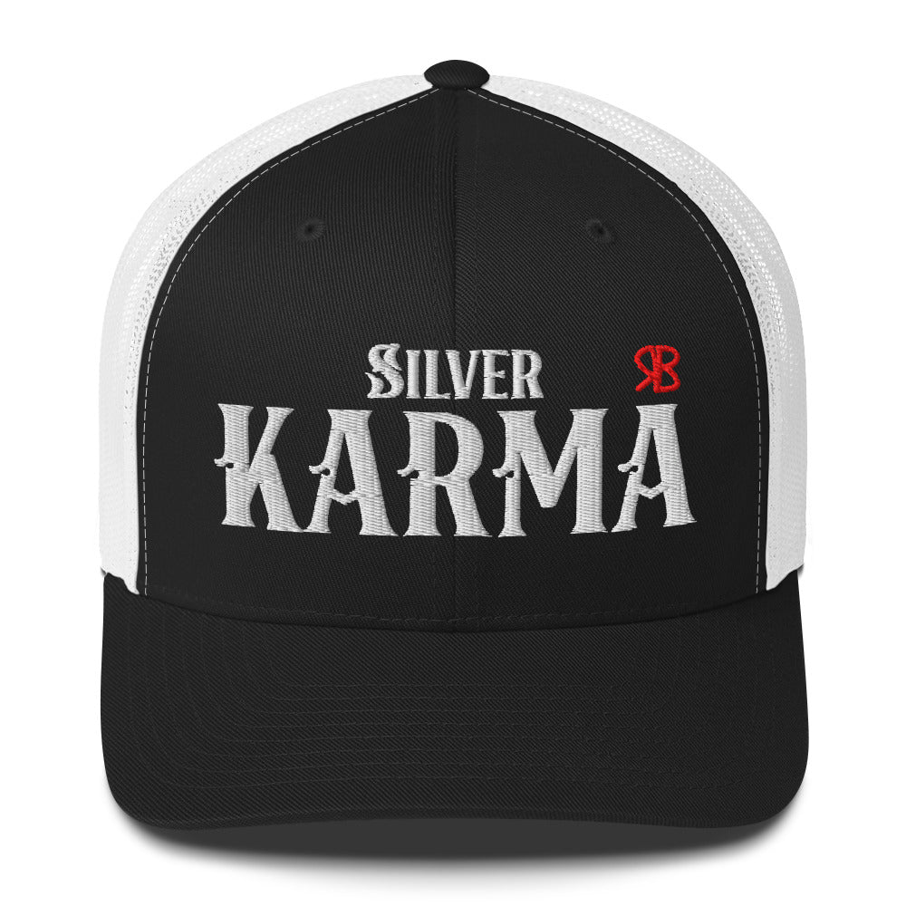 black/white retro trucker cap with mesh back. The front features bold white embroidered text reading "SILVER KARMA" with a small red RB logo to the right.