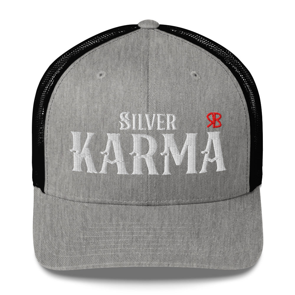 light grey/black retro trucker cap with mesh back. The front features bold white embroidered text reading "SILVER KARMA" with a small red RB logo to the right.