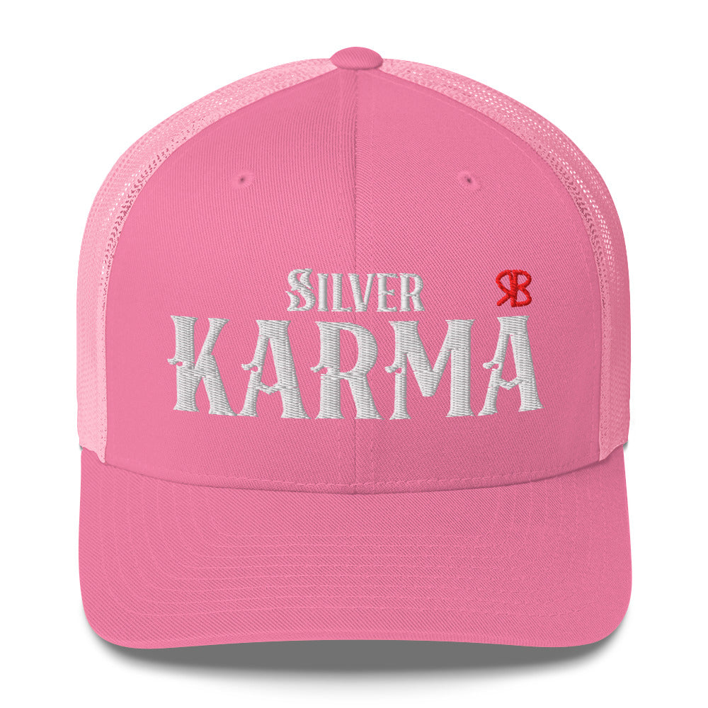 pink/white retro trucker cap with mesh back. The front features bold white embroidered text reading "SILVER KARMA" with a small red RB logo to the right.
