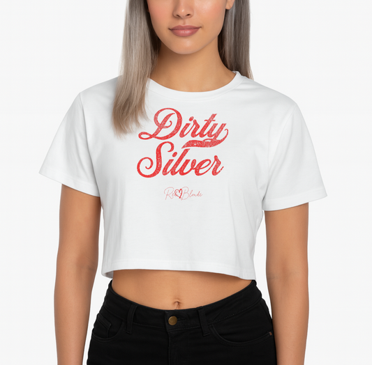 Silver haird model wears a white women’s crop top featuring the phrase “Dirty Silver” in bold, red milkstore vintage-style script across the chest. Below the phrase, the brand name “RedBlonde” is printed in a smaller, elegant handwritten font.