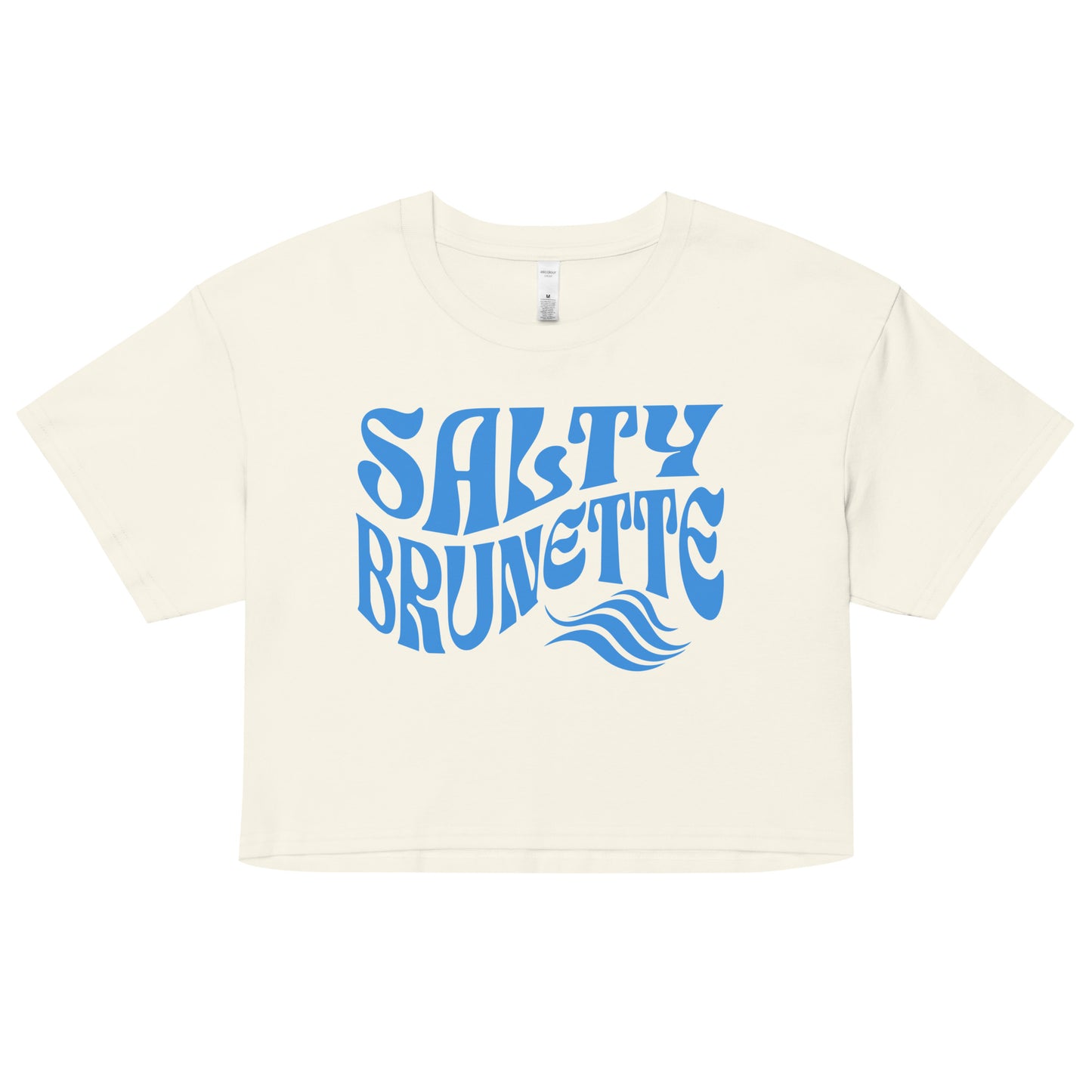 Flatlay of a soft beige loose women's crop top t-shirt with the words ‘Salty Brunette' in blue retro 70s font