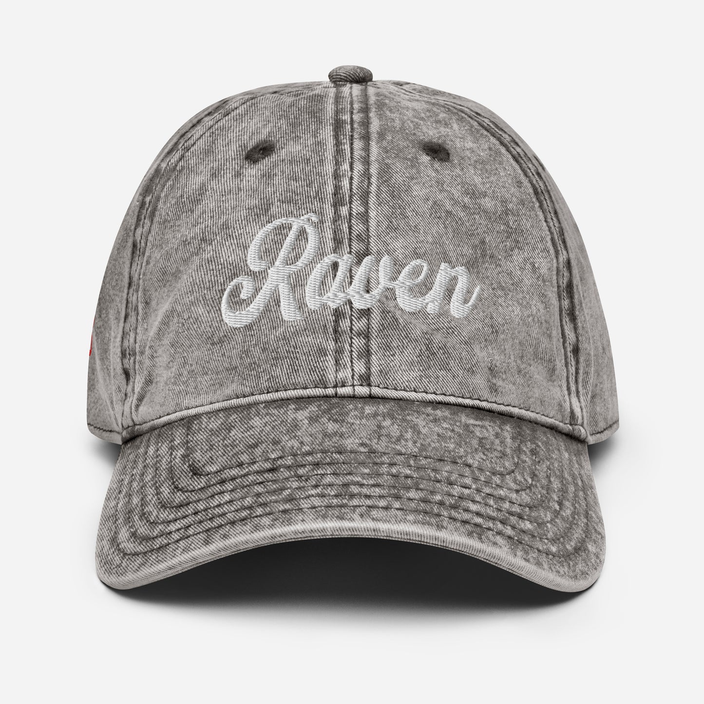 flatlay of vintage black / grey denim wash effect baseball cap with the word 'Raven' embroidered on the front in white adventure type script font