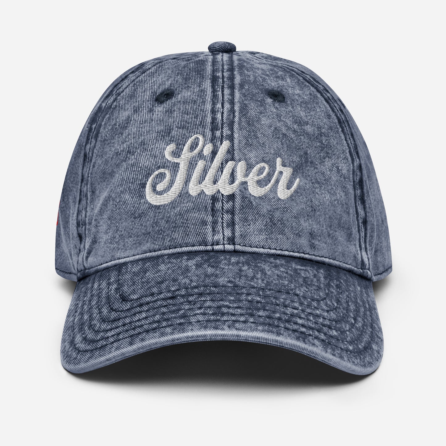 flatlay of vintage blue denim wash effect baseball cap with the word 'Silver' embroidered on the front in white adventure type script font