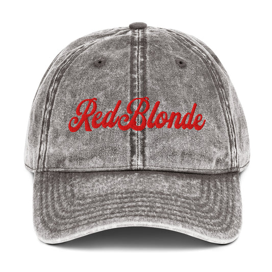 flatlay of vintage grey denim wash effect baseball cap with the word 'RedBlonde' embroidered on the front in white adventure type script font
