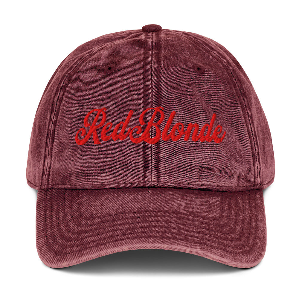 flatlay of vintage maroon denim wash effect baseball cap with the word 'RedBlonde' embroidered on the front in white adventure type script font