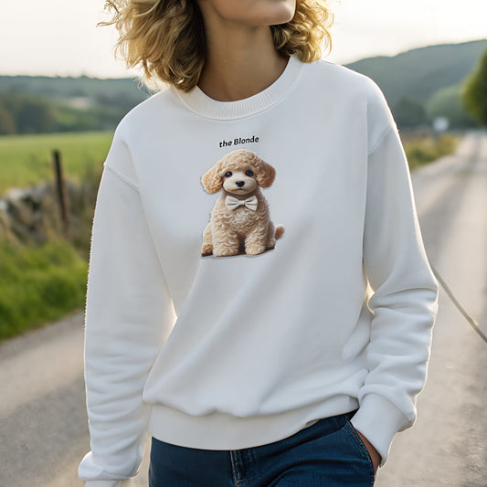 Model with blonde hair wearing white relaxed fit unisex sweatshirt with a cute graphic of a blonde puppy wearing a bow-tie and the words 'the Blonde' linking to blonde hair. Branded RedBlonde in red on inside neck and right cuff