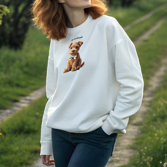 Model with red hair wearing white relaxed fit unisex sweatshirt with a cute graphic of a ginger puppy wearing a bow-tie and the words 'the Redhead' linking to ginger hair. Branded RedBlonde in red on inside neck and right cuff