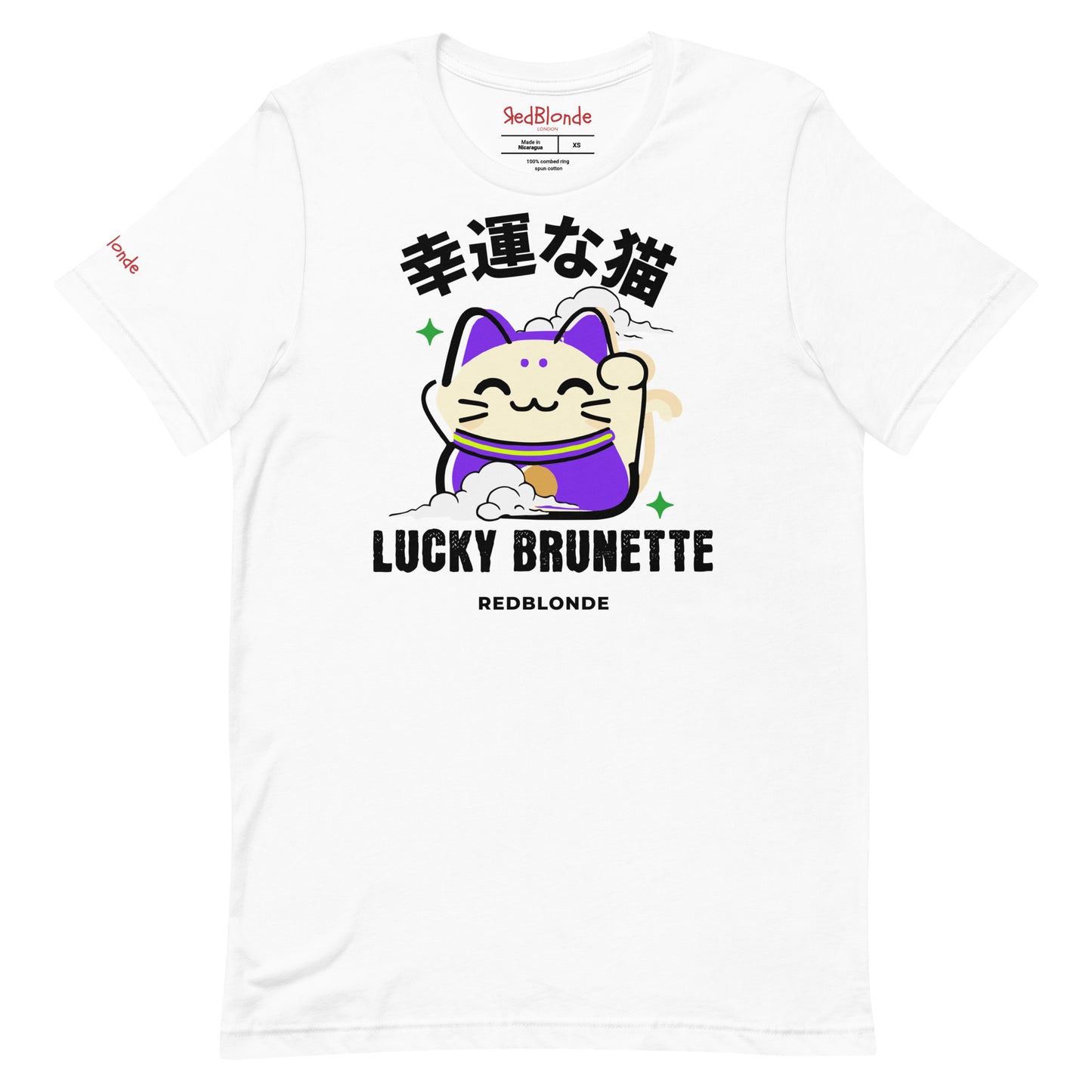 A white unisex T-shirt with a classic crew neckline and short sleeves. The front features a colorful graphic of a waving Maneki-neko (lucky cat) in cream and purple, surrounded by small green sparkles. Above the cat, bold black Japanese characters are displayed. Below the cat, the text reads “LUCKY BRUNETTE” in black block letters, with “REDBLONDE” printed underneath in smaller font. Branded RedBlonde in red inside neck and right sleeve