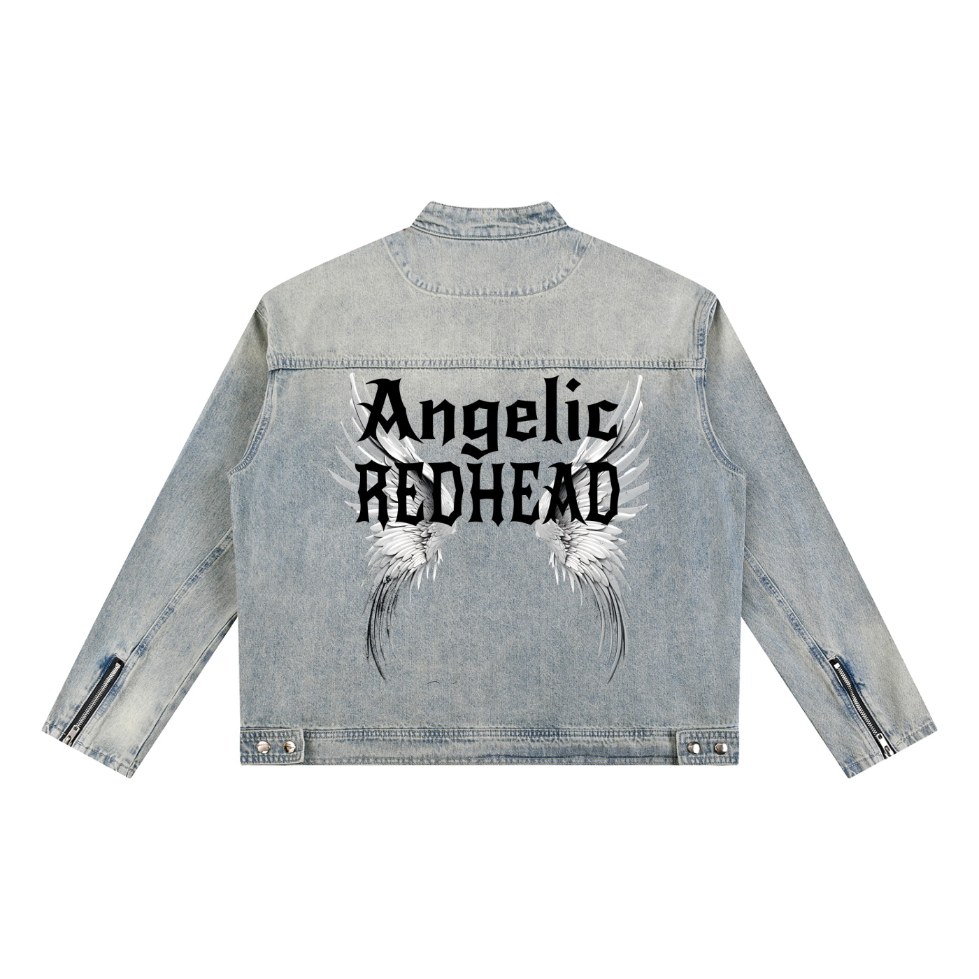 A light-wash denim jacket shown from the back on a white background. The sleeves have zippered cuffs, and the back features a large graphic with white angel wings and black gothic New Rocker style text reading “Angelic REDHEAD.”