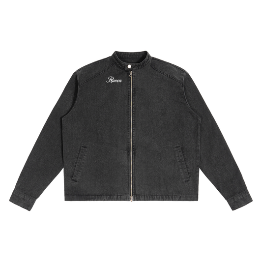 A washed-black denim jacket with a straight, boxy cut and a stand collar. The front features a full silver zip, two slanted pockets, and white embroidered text on the left chest that reads "Raven" in Milkstore script 