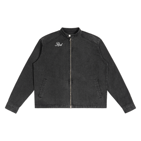 A washed-black denim jacket with a straight, boxy cut and a stand collar. The front features a full silver zip, two slanted pockets, and white embroidered text on the left chest that reads "Red" in Milkstore script 