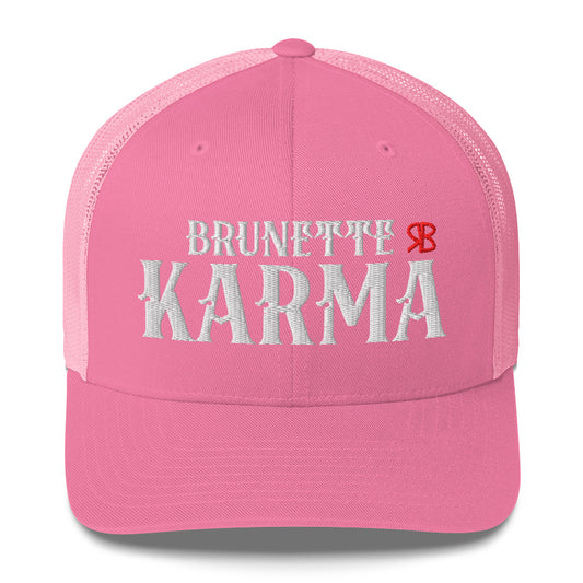 pink/white retro trucker cap with mesh back. The front features bold white embroidered text reading "BRUNETTE KARMA" with a small red RB logo to the right.