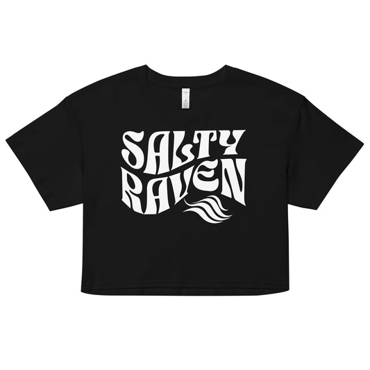 Flatlay of a black loose crop top t-shirt with the words ‘Salty Raven’ in white retro 70s wavy font