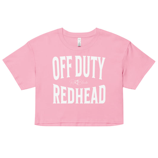 Flatlay of a pink women's crop top  graphic t-shirt with “OFF DUTY REDHEAD” in white Helvetica Now font emblazoned on the front, signed off RedBlonde