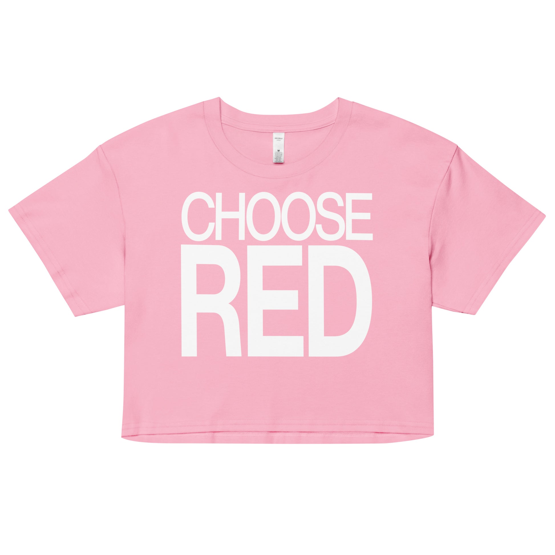 Flatlay of a pink women's crop top  graphic t-shirt with “CHOOSE RED” in white Helvetica Now font emblazoned on the front. 