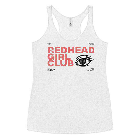 Heather white women’s racerback tank top with bold red DT Getai Grotesh text reading “Redhead Girl Club” and a stylized black eye graphic to the right. Additional smaller text includes phrases like “Brains First,” “Blonde Always,” “Born to Be Bold,” and “ESTD 2025” arranged around the design.