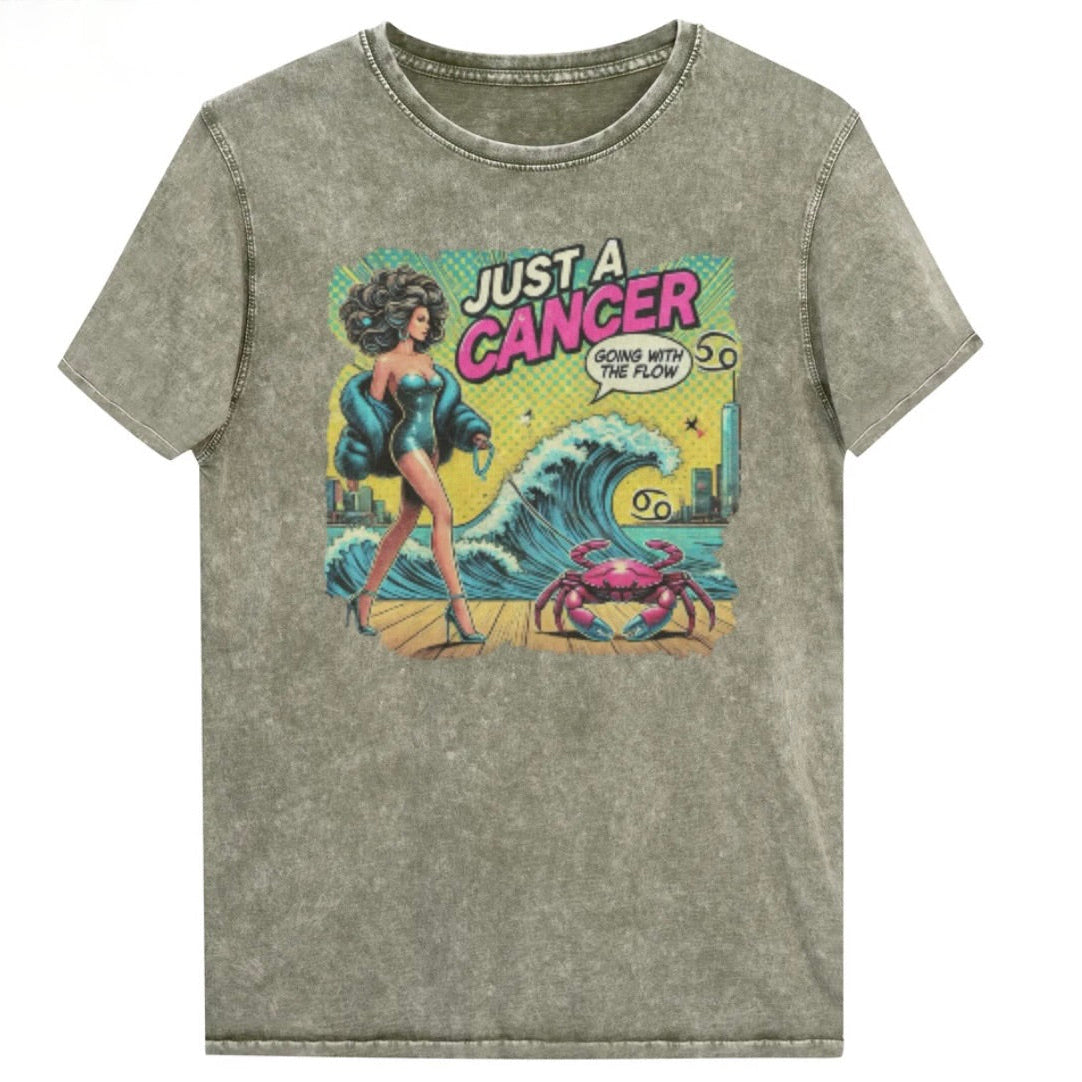 Flatlay of a unisex army green denim wash vintage t-shirt with a retro pop-art Cancer graphic featuring a dark-haired woman, wearing a turquoise short strapless catsuit, fur coat and strappy heels, walking a pink crab on a leash, with a high water wave and city backdrop captioned Just an Caner, Going with the Flow'. Branded RedBlonde on inside neck and right sleeve 