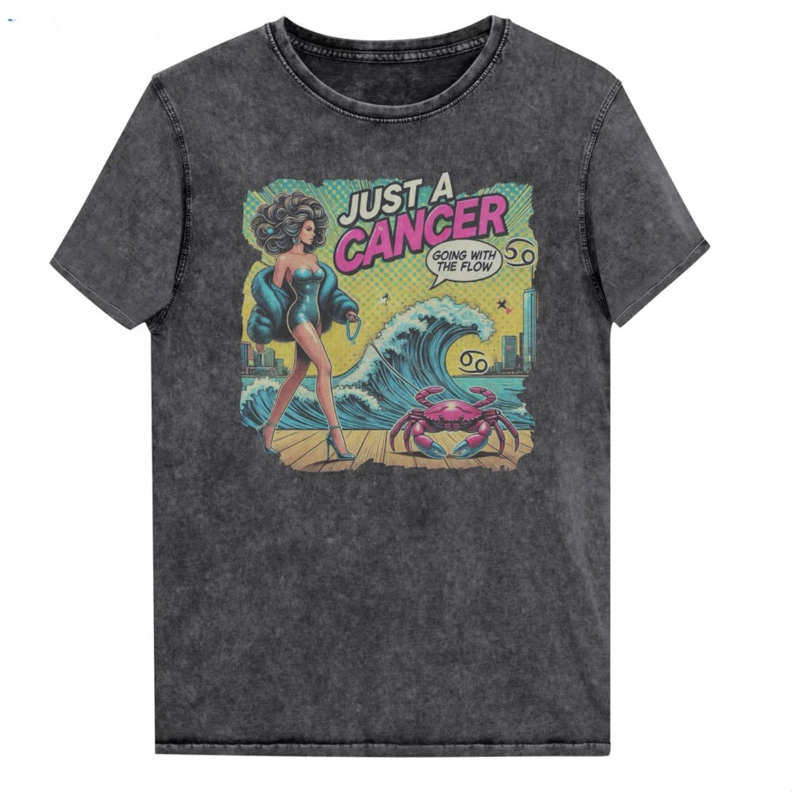 Flatlay of a unisex black denim wash vintage t-shirt with a retro pop-art Cancer graphic featuring a dark-haired woman, wearing a turquoise short strapless catsuit, fur coat and strappy heels, walking a pink crab on a leash, with a high water wave and city backdrop captioned Just an Caner, Going with the Flow'. Branded RedBlonde in red on inside neck and right sleeve 