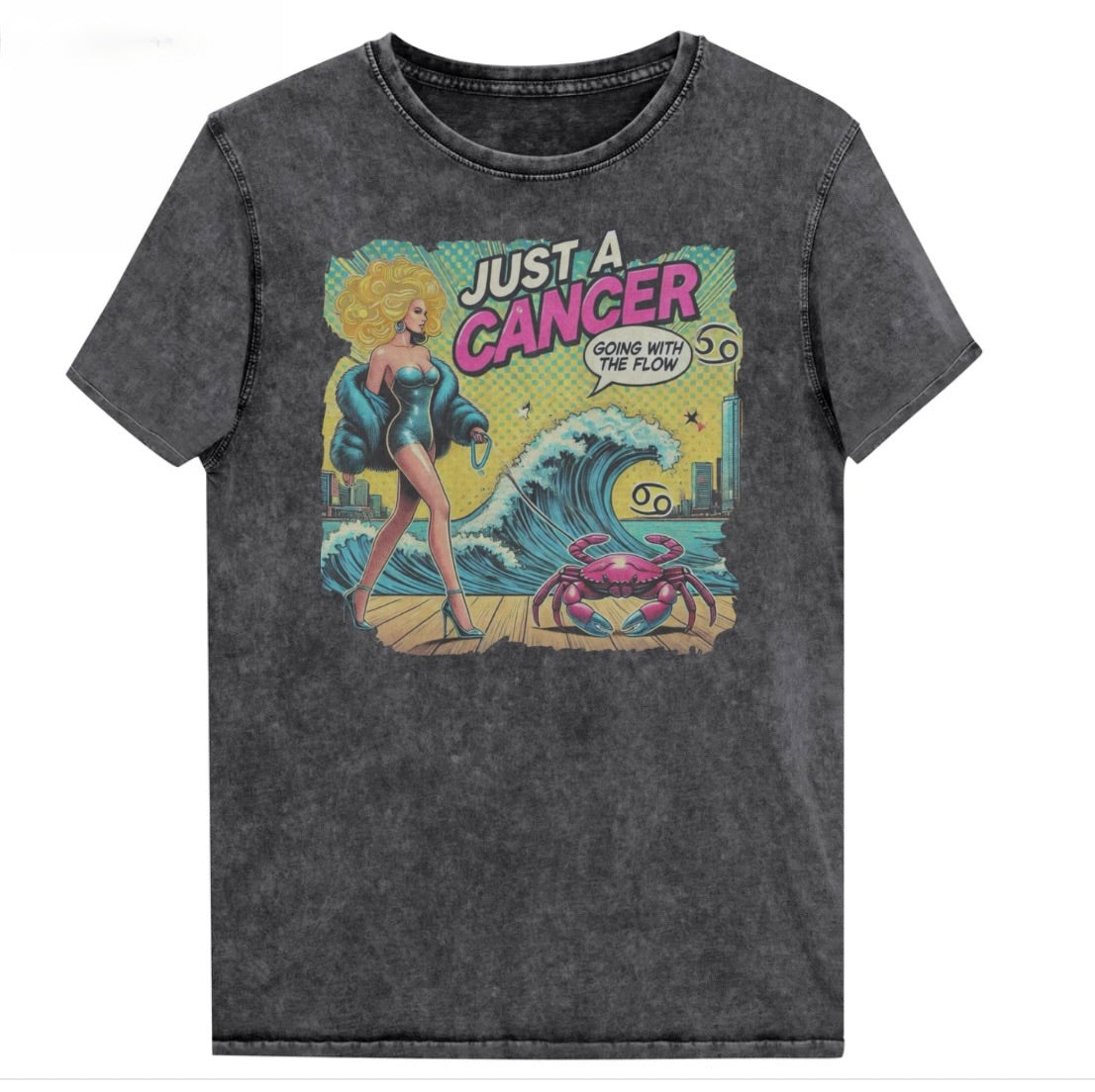 Flatlay of a unisex black denim wash vintage t-shirt with a retro pop-art Cancer graphic featuring a blonde woman, wearing a turquoise short strapless catsuit, fur coat and strappy heels, walking a pink crab on a leash, with a high water wave and city backdrop captioned Just an Caner, Going with the Flow'. Branded RedBlonde in red on inside neck and right sleeve 