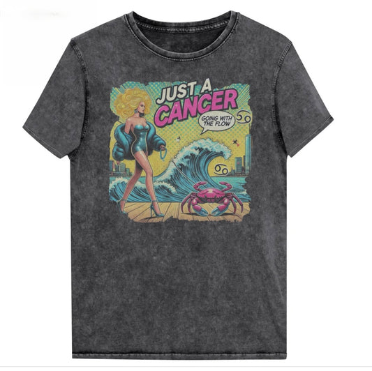 Flatlay of a unisex black denim wash vintage t-shirt with a retro pop-art Cancer graphic featuring a blonde woman, wearing a turquoise short strapless catsuit, fur coat and strappy heels, walking a pink crab on a leash, with a high water wave and city backdrop captioned Just an Caner, Going with the Flow'. Branded RedBlonde in red on inside neck and right sleeve 