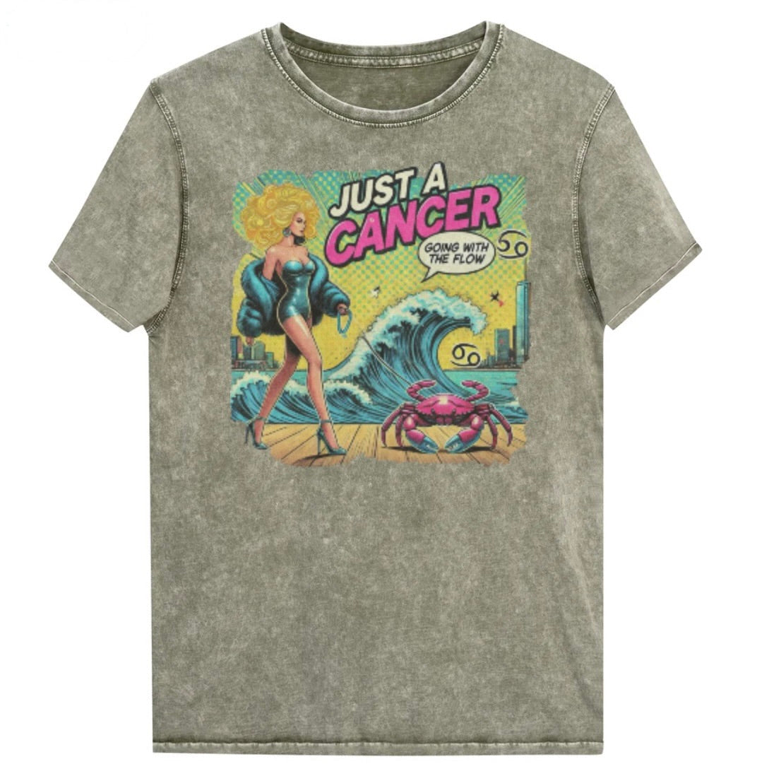 Flatlay of a unisex army green denim wash vintage t-shirt with a retro pop-art Cancer graphic featuring a blonde woman, wearing a turquoise short strapless catsuit, fur coat and strappy heels, walking a pink crab on a leash, with a high water wave and city backdrop captioned Just an Caner, Going with the Flow'. Branded RedBlonde in red on inside neck and right sleeve 