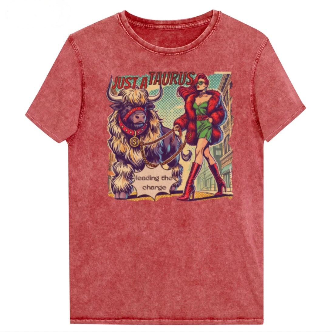 Flatlay of a unisex relaxed fit garnet red  vintage denim wash t-shirt with a retro pop-art taurus graphic featuring a redhead woman with long flowing straight hair, wearing a green dress with a red belt, red high-heeled boots and red fur coat, walking a furry bull with a red collar and medallion in city street captioned ‘Just a taurus leading the charge'. randed RedBlonde on inside neck and right shoulder