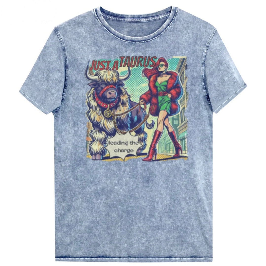 Flatlay of a unisex relaxed fit vintage blue denim wash t-shirt with a retro pop-art taurus graphic featuring a redhead woman with long flowing straight hair, wearing a green dress with a red belt, red high-heeled boots and red fur coat, walking a furry bull with a red collar and medallion in city street captioned ‘Just a taurus leading the charge'. randed RedBlonde on inside neck and right shoulder
