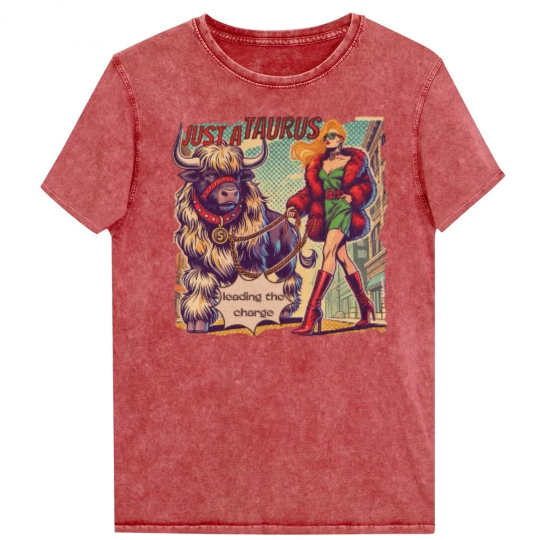 Flatlay of a unisex relaxed fit garnet red vintage denim wash t-shirt with a retro pop-art taurus graphic featuring a blonde woman with long flowing straight hair, wearing a green dress with a red belt, red high-heeled boots and red fur coat, walking a furry bull with a red collar and medallion in city street captioned ‘Just a taurus leading the charge'. Branded RedBlonde in red on inside neck and right shoulder