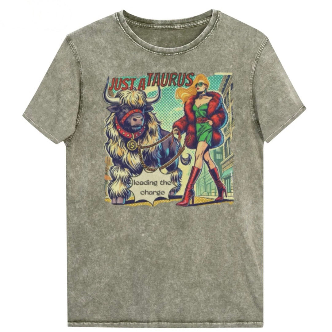 Flatlay of a unisex relaxed fit army green vintage denim wash t-shirt with a retro pop-art taurus graphic featuring a blonde woman with long flowing straight hair, wearing a green dress with a red belt, red high-heeled boots and red fur coat, walking a furry bull with a red collar and medallion in city street captioned ‘Just a taurus leading the charge'. Branded RedBlonde in red on inside neck and right shoulder