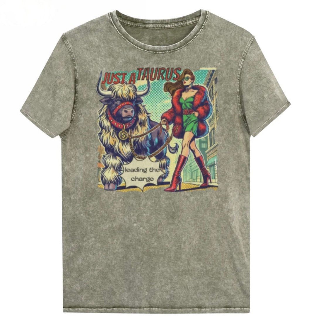 Flatlay of a unisex relaxed fit army green vintage denim wash t-shirt with a retro pop-art taurus graphic featuring a brunette woman with long flowing straight hair, wearing a green dress with a red belt, red high-heeled boots and red fur coat, walking a furry bull with a red collar and medallion in city street captioned ‘Just a taurus leading the charge'. Branded RedBlonde on inside neck and right shoulder
