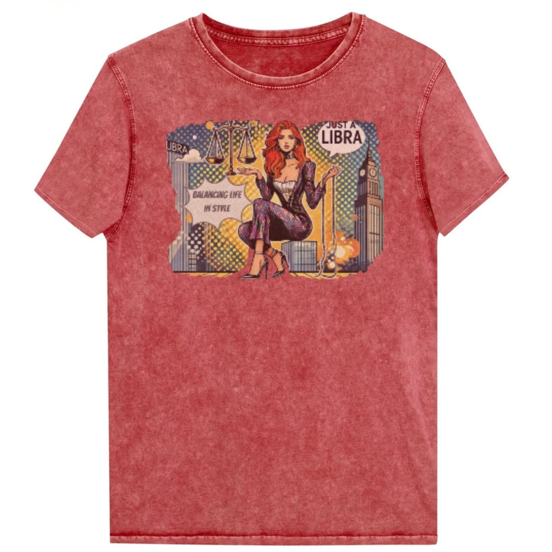 Flatlay of a unisex red garnet denim wash vintage t-shirt with a retro pop-art redhead Libra graphic featuring a redhead woman, scales, and a city backdrop, captioned ‘Just a Libra, Balancing Life in Style’. Branded RedBlonde on inside neck and right sleeve
