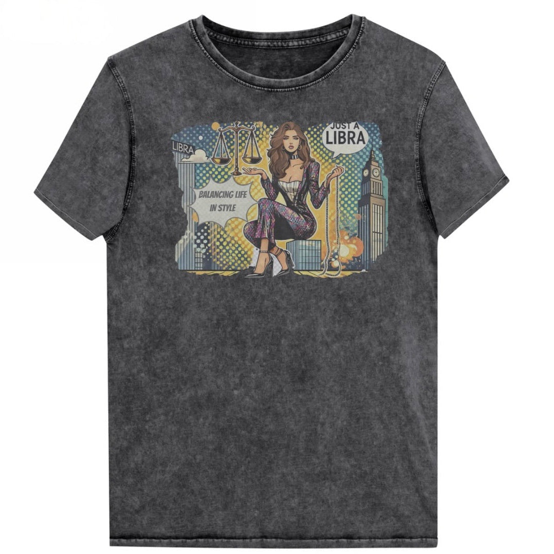 Flatlay of a unisex black denim wash vintage t-shirt with a retro pop-art Libra graphic featuring a brunette woman, scales, and a city backdrop, captioned ‘Just a Libra, Balancing Life if Style’. Branded RedBlonde on inside neck and right sleeve