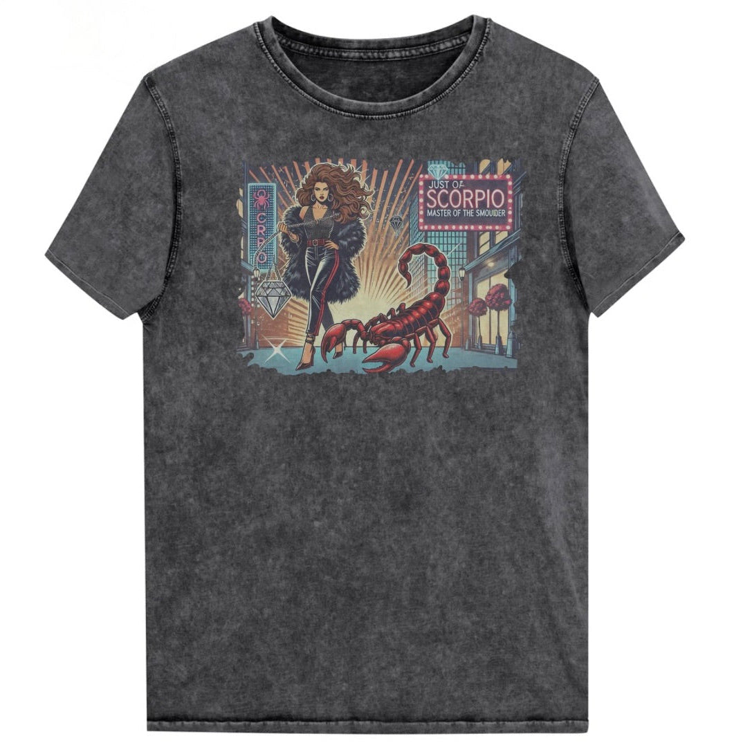 Flatlay of a unisex black denim wash vintage t-shirt with a retro pop-art Scorpio graphic featuring a Brunette woman with long flowing hair, wearing a black pants with a red stripe down the side, a halterneck top and fur coat, next to a large red scorpion walking down the street past a shop window  captioned ‘Just an Scorpio, Master of the Smoulder'. Branded RedBlonde on inside neck and right shoulder