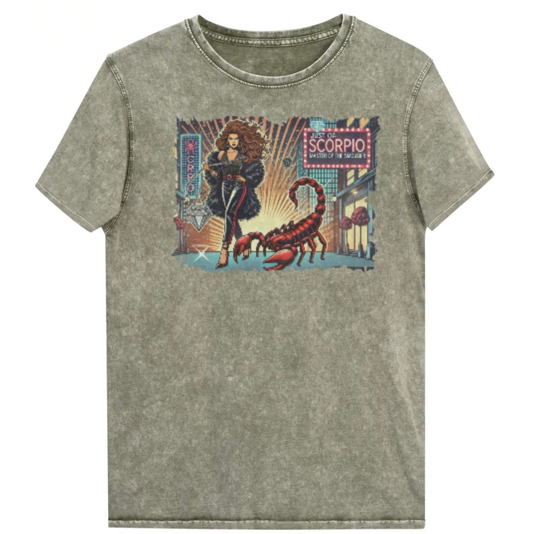 Flatlay of a unisex army green denim wash vintage t-shirt with a retro pop-art Scorpio graphic featuring a Brunette woman with long flowing hair, wearing a black pants with a red stripe down the side, a halterneck top and fur coat, next to a large red scorpion walking down the street past a shop window  captioned ‘Just an Scorpio, Master of the Smoulder'. Branded RedBlonde on inside neck and right shoulder
