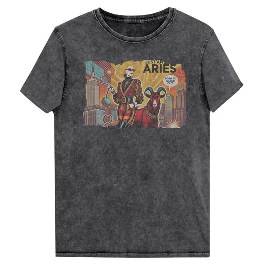 Flatlay of a unisex black denim wash vintage t-shirt with a retro pop-art Aries graphic featuring a blonde woman, wearing a belted catsuit and high boots with one hand in her pocket, with a ram by her side and a city backdrop, captioned ‘Just an Aries, born to stand out'. Branded RedBlonde on inside neck and right sleeve
